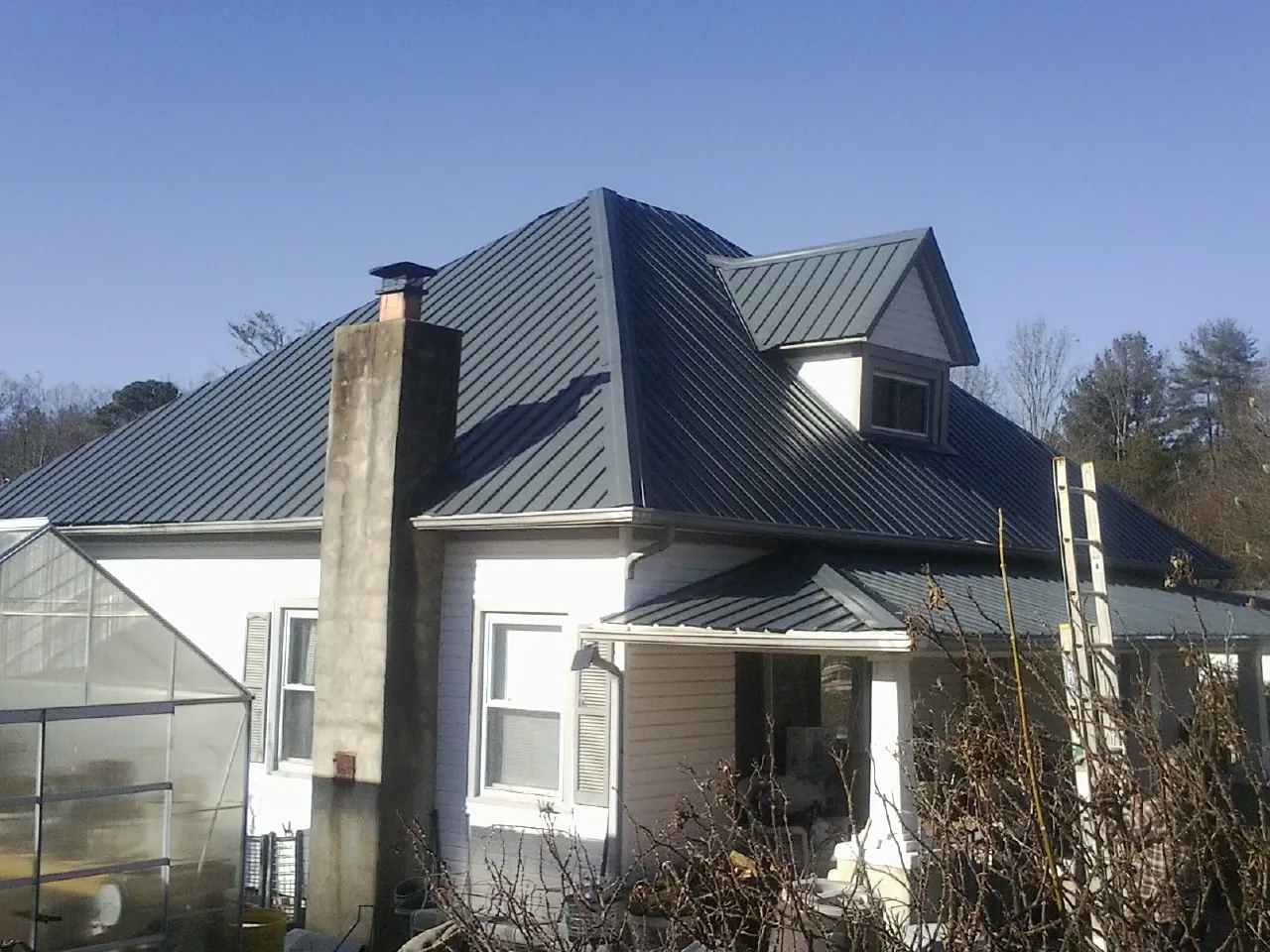 Dark blue standing seam metal roof on a white farmhouse with dormer — Slate & Tile Roof Repair by Roofing Brothers in Sierra Madre