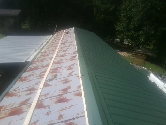 Old rusted panels beside newly installed green metal roofing — Wind Damage Roof Repair by Roofing Brothers in Sierra Madre