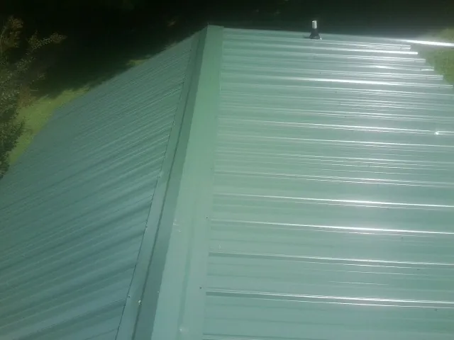 New green metal panels meeting at the ridge of a roof — Flat Roof Repair work by our crew in Sierra Madre