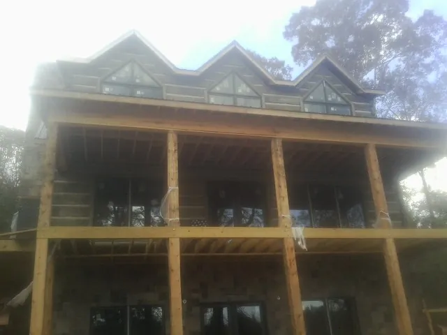 Dormers and porch framing on a large log home under construction — Roof Coating work by our crew in Sierra Madre