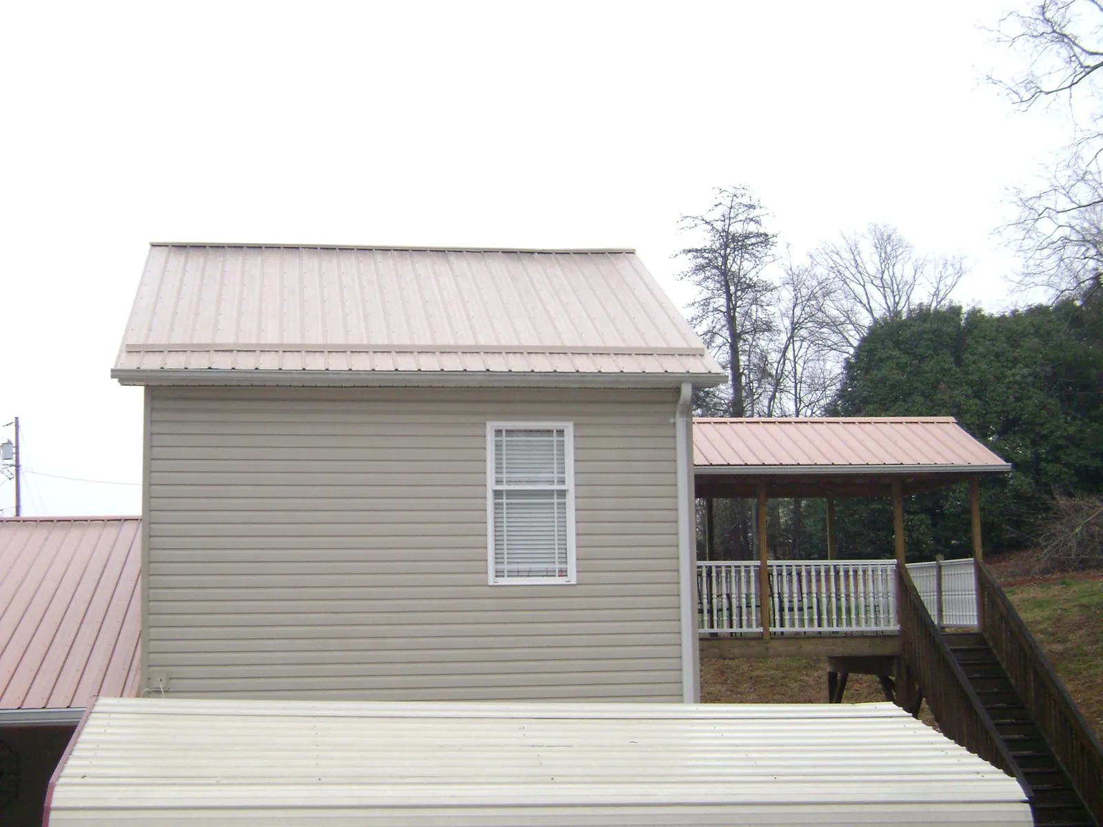 Tan metal roofs on a two story addition and attached porch, from a Roof Replacement job in Sierra Madre