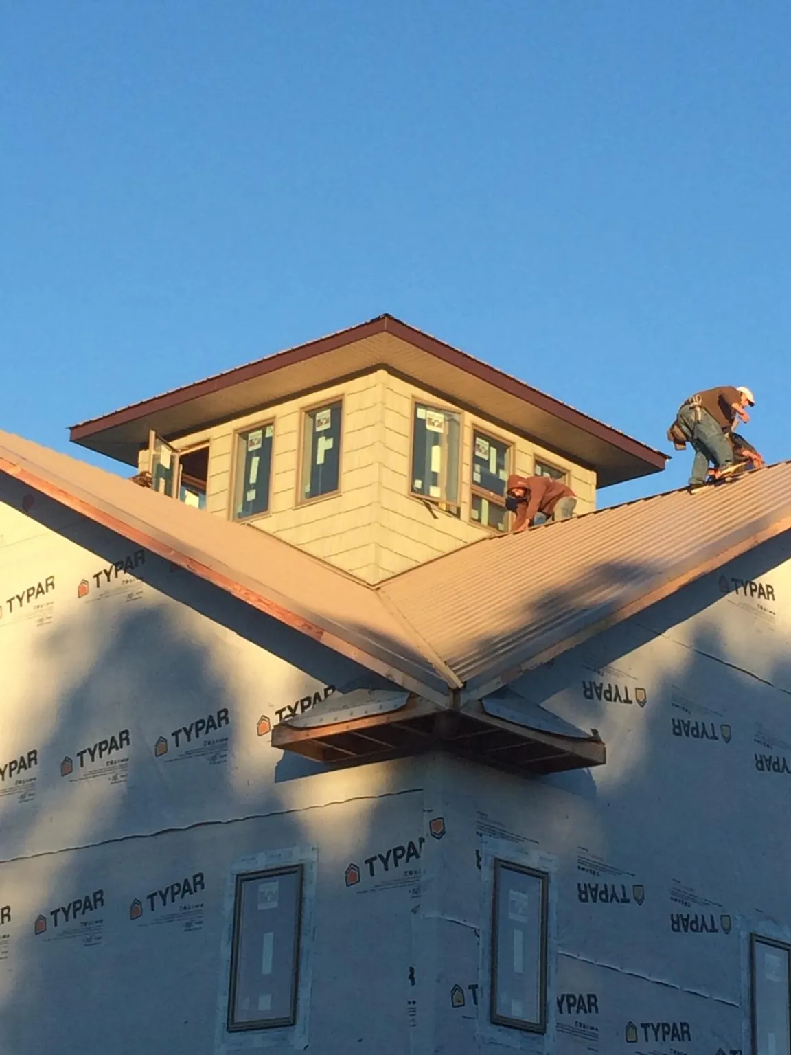 Roofers working around a rooftop cupola on a new metal roof at sunset — Roof Waterproofing in Sierra Madre by Roofing Brothers